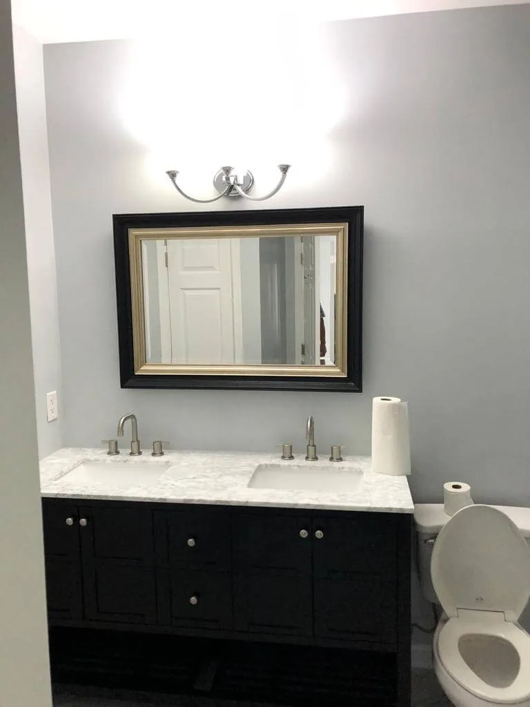 Completed bathroom with black vanity, mirror and updated lighting