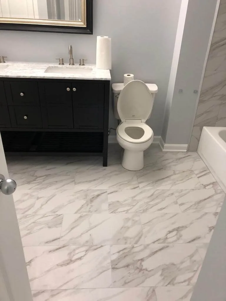 Updated bathroom with marble-look floor, black vanity and finished surfaces