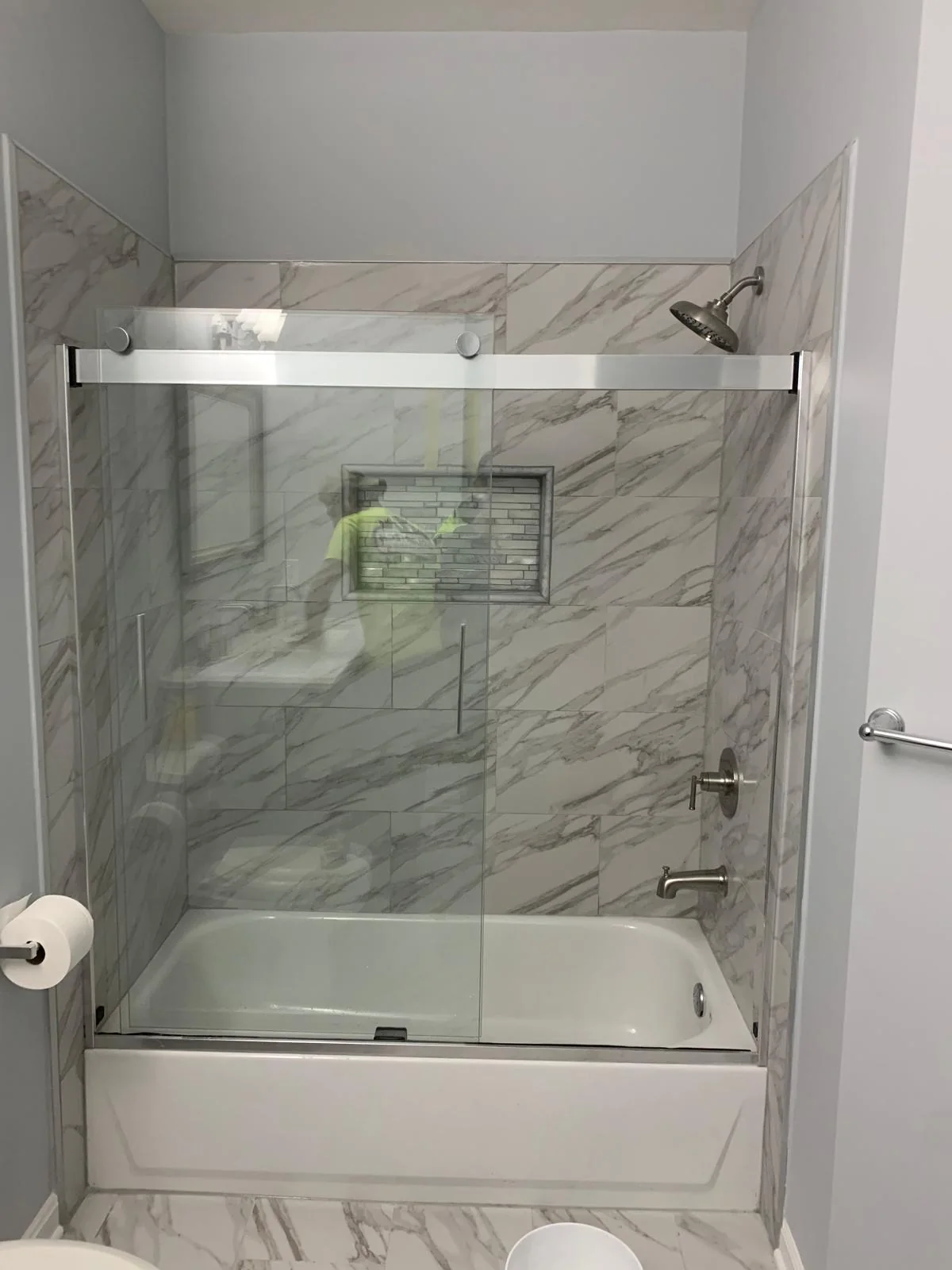 Bathroom with glass tub enclosure and marble-look tile surround