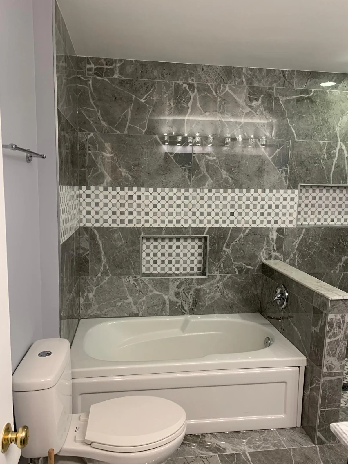 Alternate view of gray tiled bathroom with tub and vanity