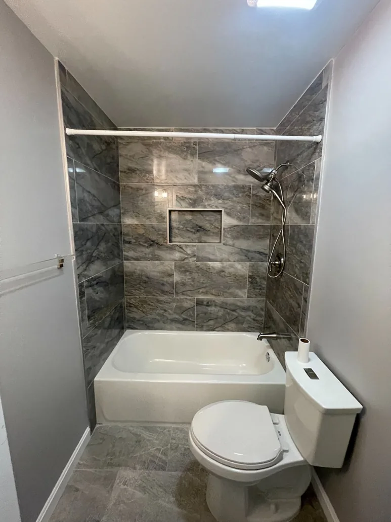 Completed bathroom with tiled tub surround, vanity and new finishes