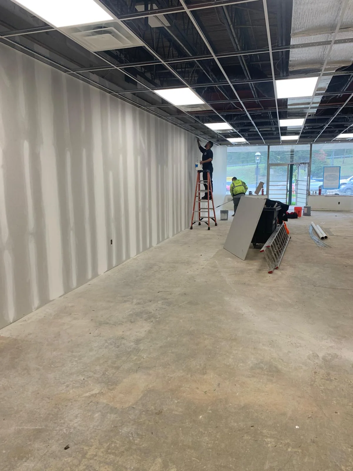 Commercial corridor with taped drywall seams and exposed ceiling systems