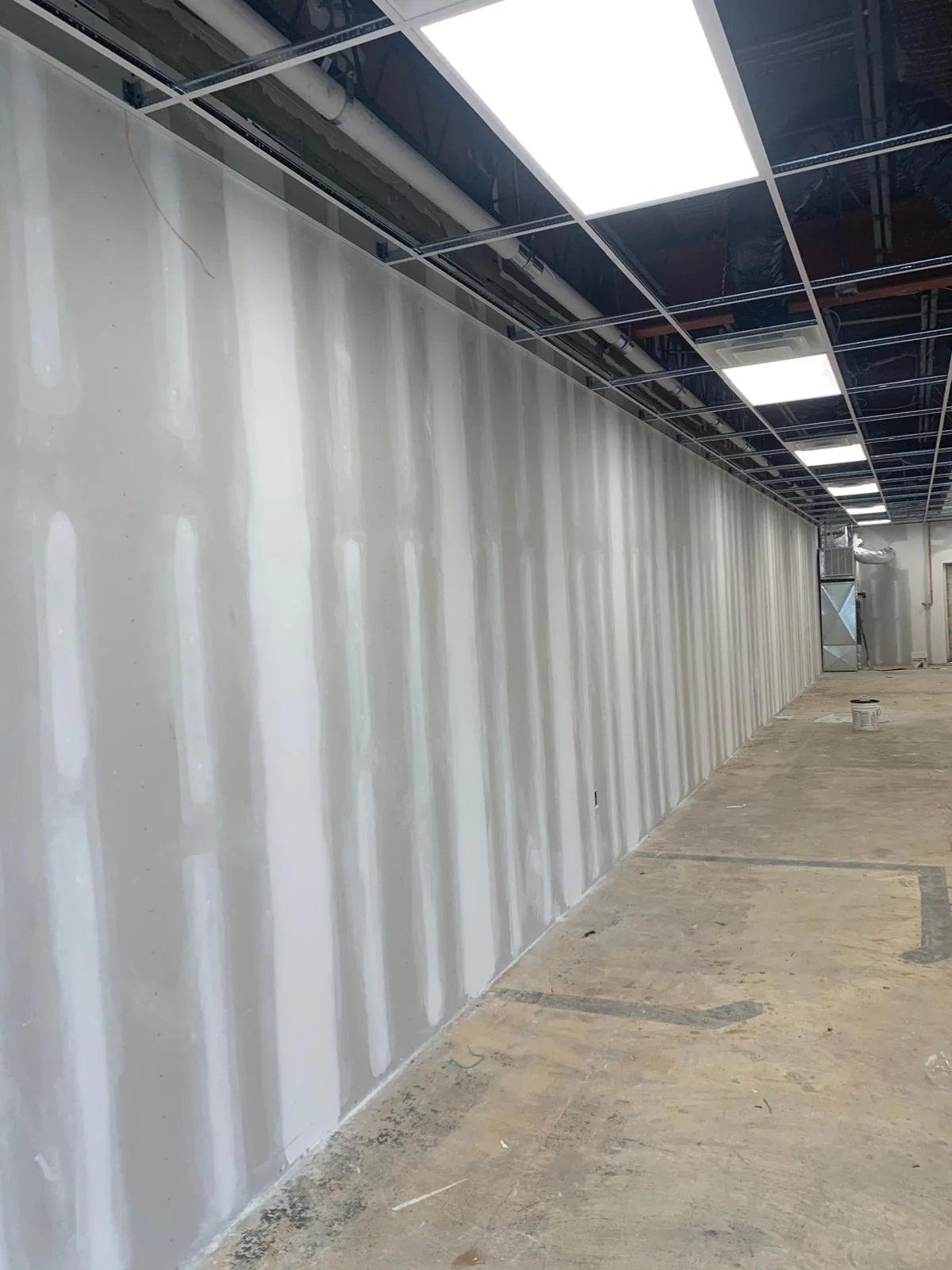 Commercial renovation corridor with drywall finishing and open ceiling