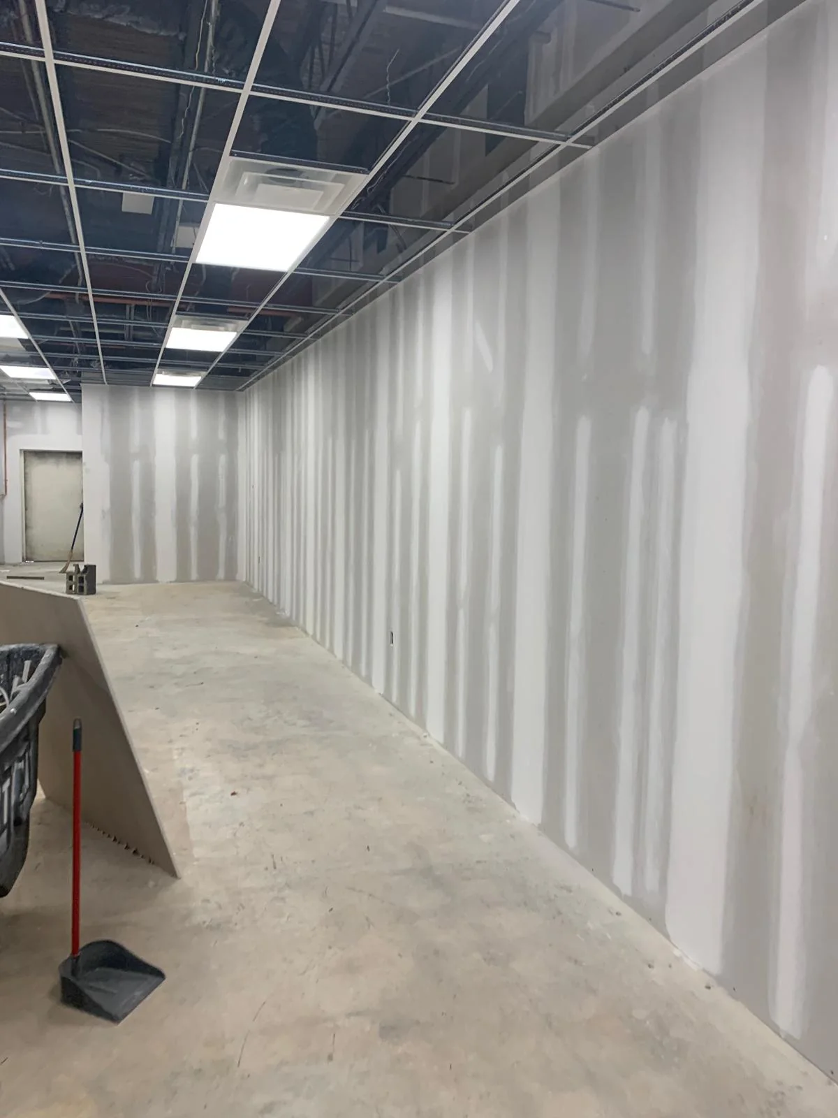 Commercial corridor with drywall finishing and exposed ceiling grid