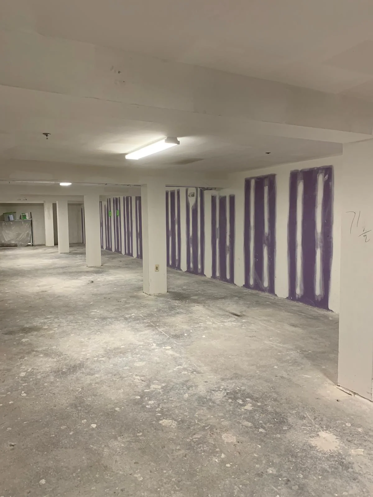 Commercial interior with drywall finishing underway across a large open space