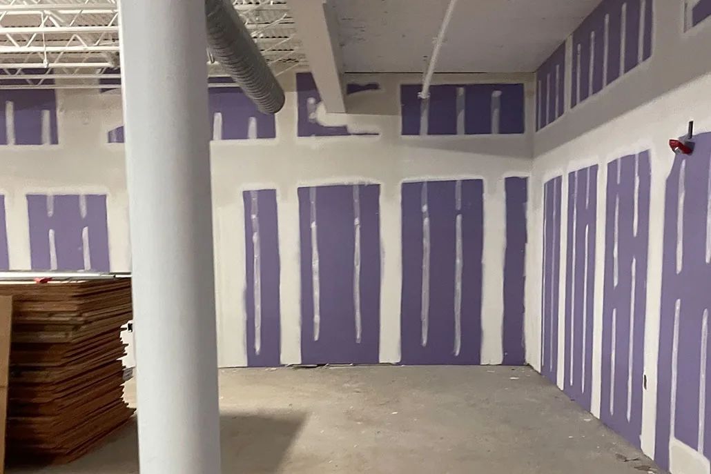 Large commercial interior with purple drywall panels and finished seams