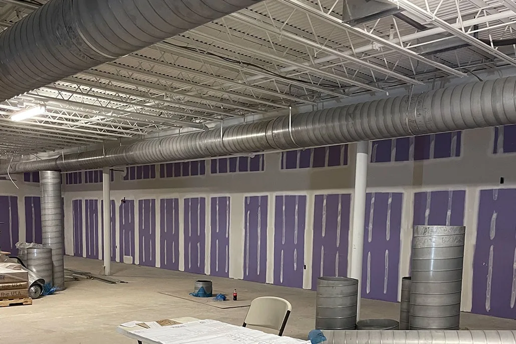 Commercial open space during drywall installation beneath exposed systems