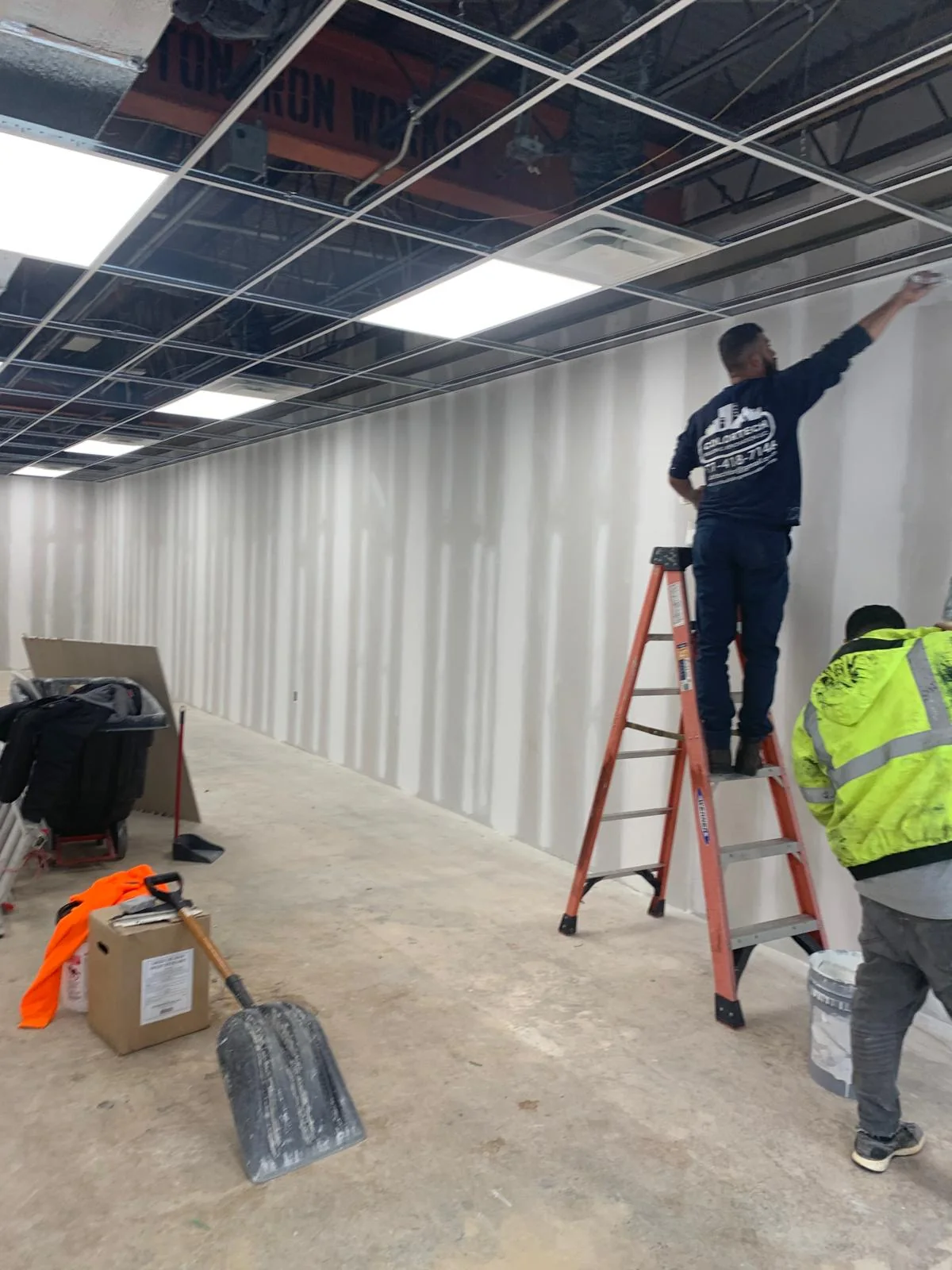 Workers completing drywall and ceiling work in a commercial interior