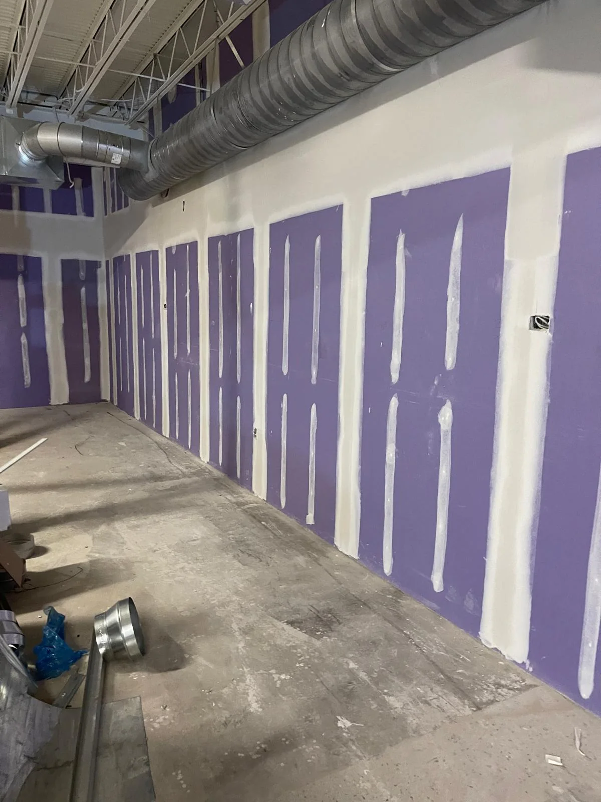 Commercial space with purple drywall panels and taped seams