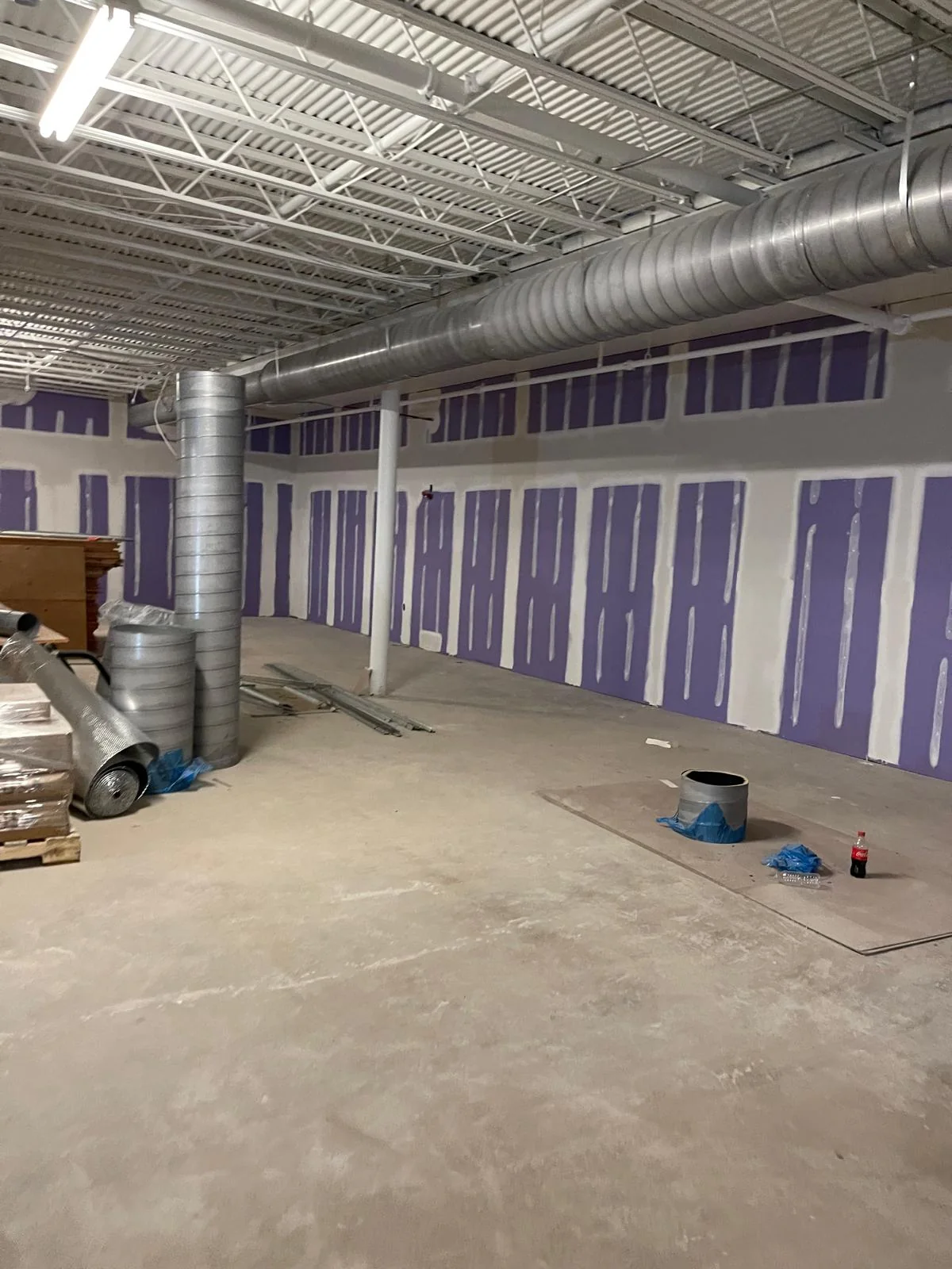 Commercial renovation space with purple drywall partitions and unfinished floor