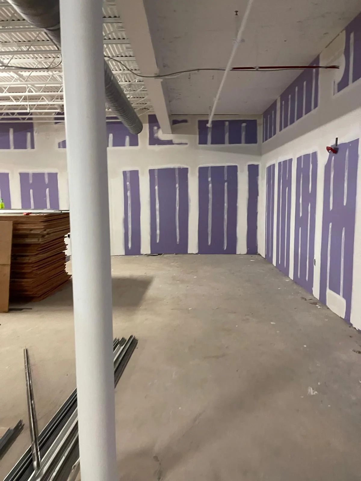 Commercial open space with purple drywall partitions and structural column