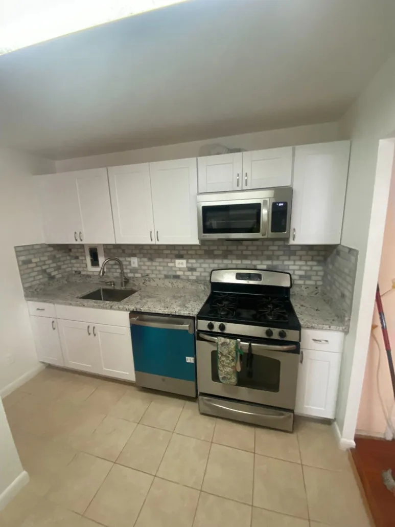 Compact completed kitchen with white cabinetry and tiled backsplash