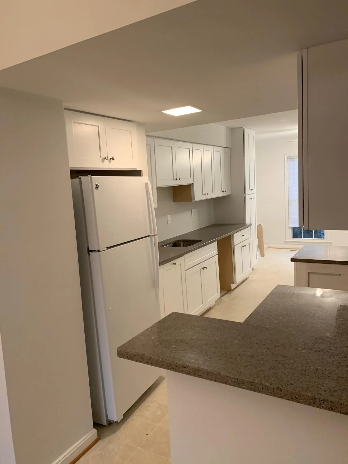 White kitchen with peninsula counter, cabinetry and stainless refrigerator