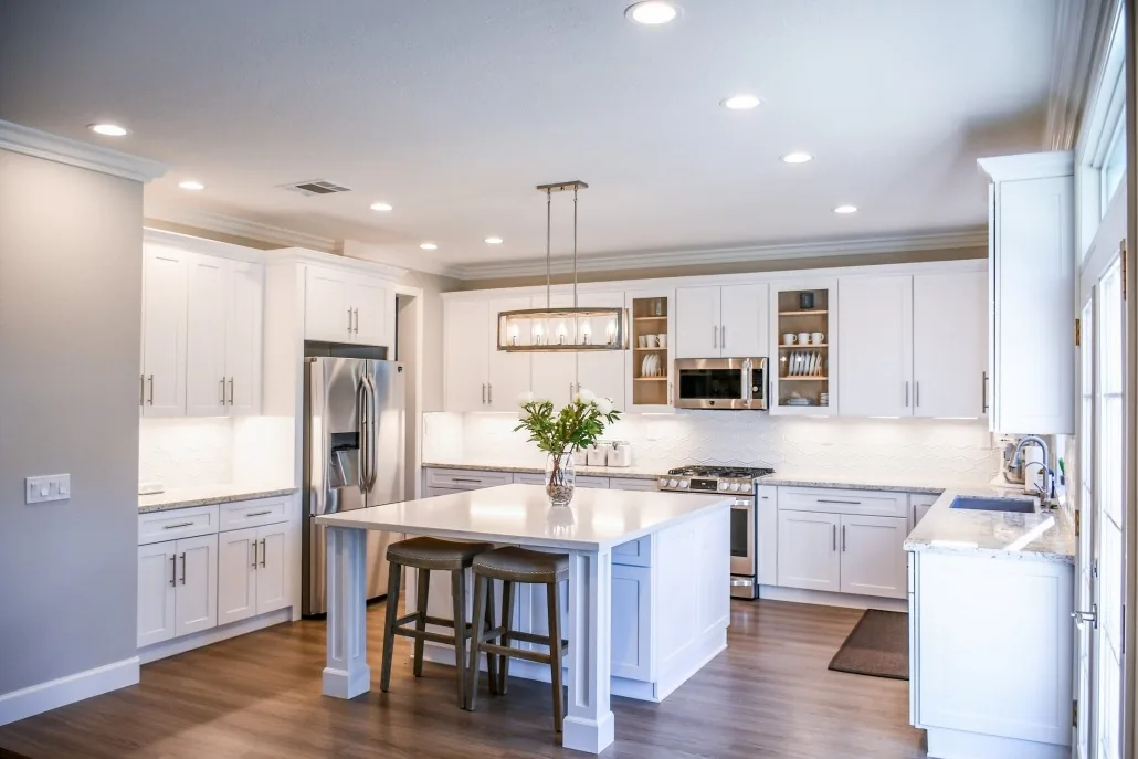 Completed open kitchen with white cabinetry, island and stainless appliances