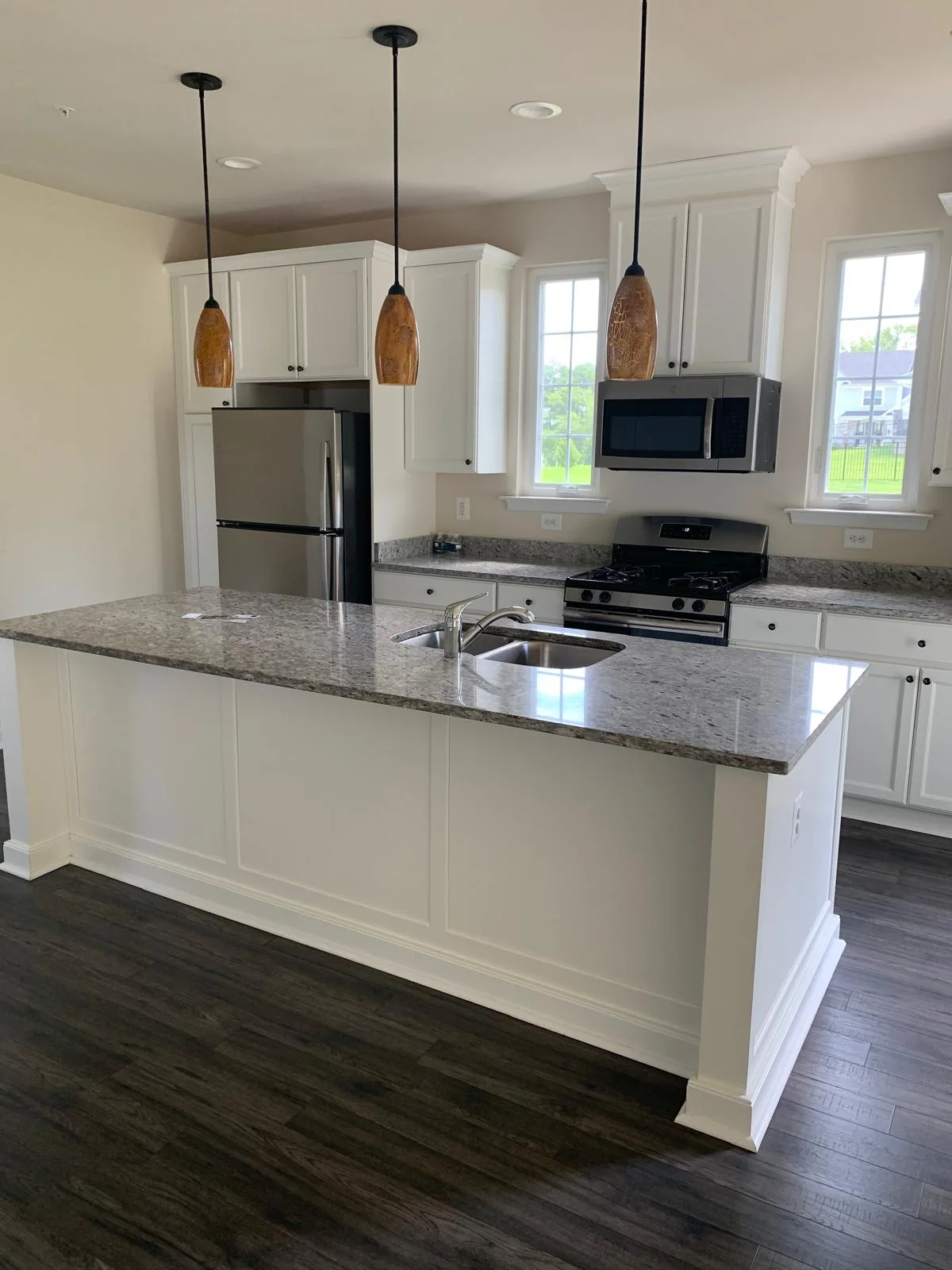 Modern white kitchen with island, pendant lights and dark flooring