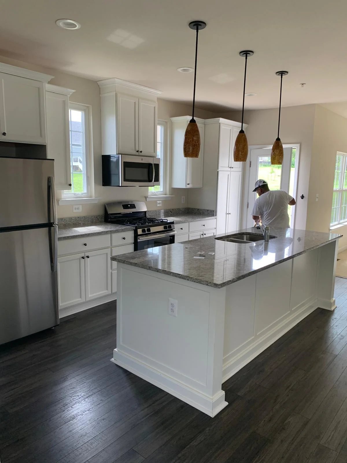White kitchen island with pendant lighting and dark flooring