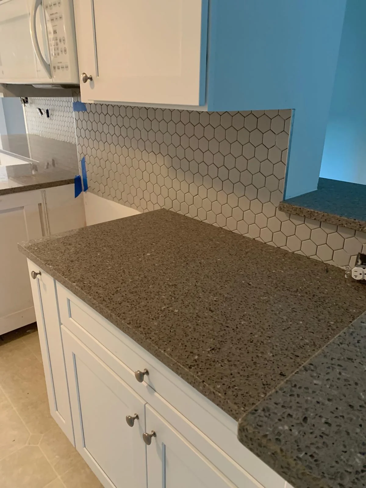 Close view of white cabinetry, backsplash and countertop finishes