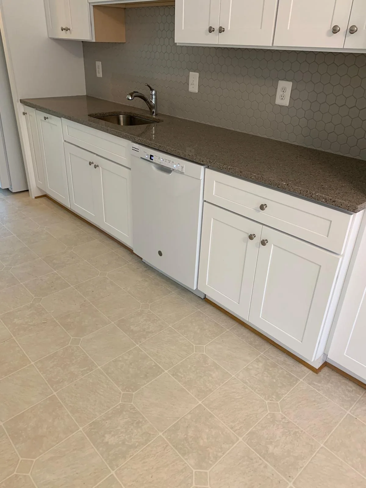 White kitchen cabinet run with stone-look counters and updated finishes