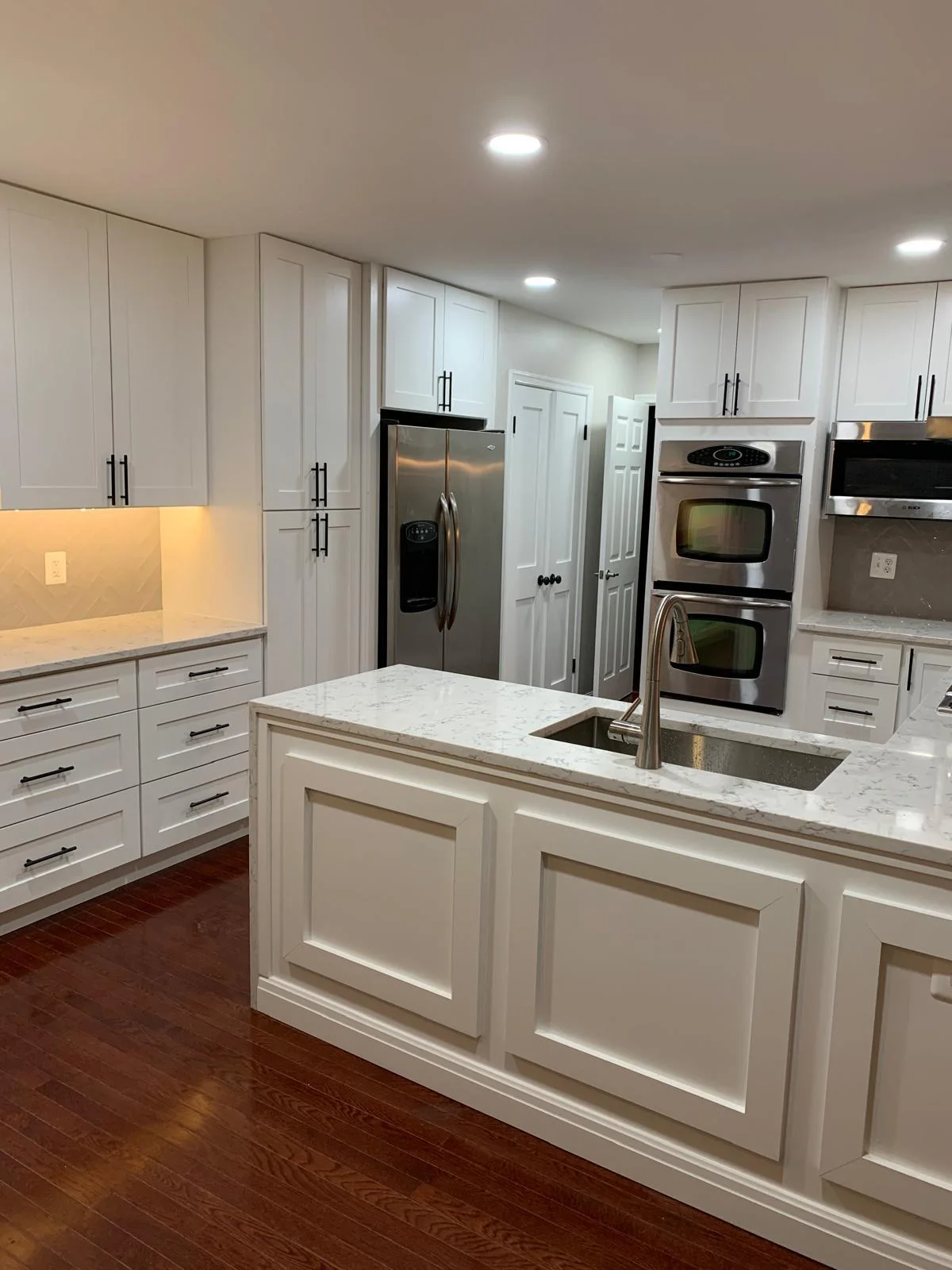 Updated white kitchen with large island, built-in appliances and stone counters