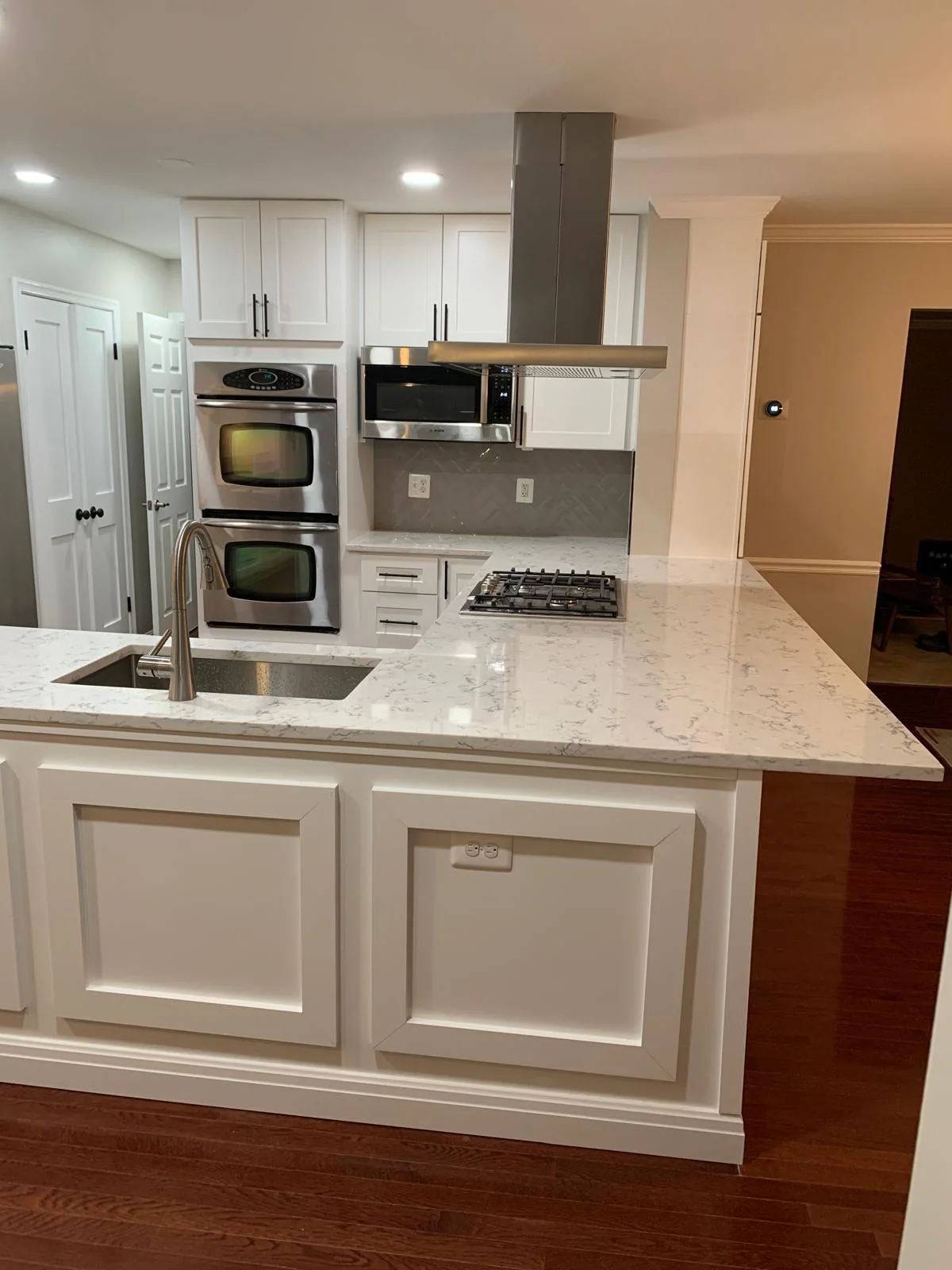 Alternate view of white kitchen island with stone surface and built-in appliances