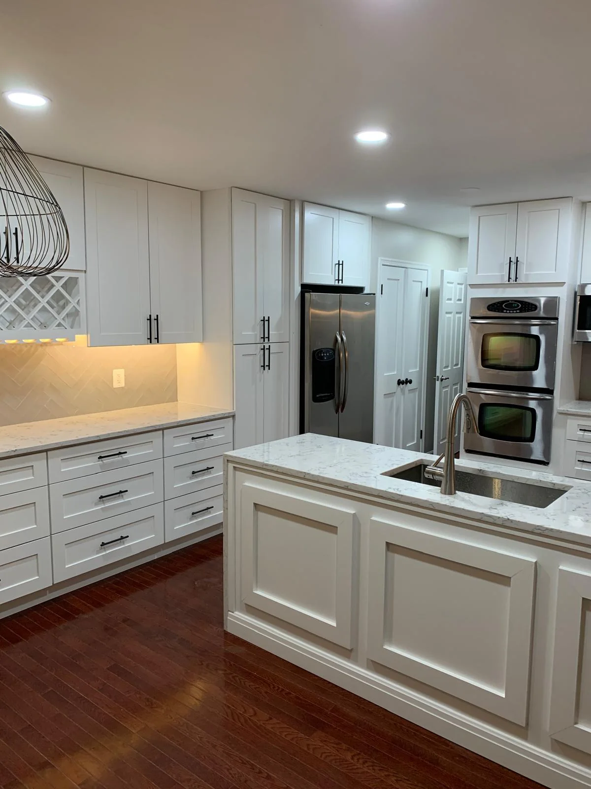 Bright white kitchen with island, cabinetry and integrated appliance wall