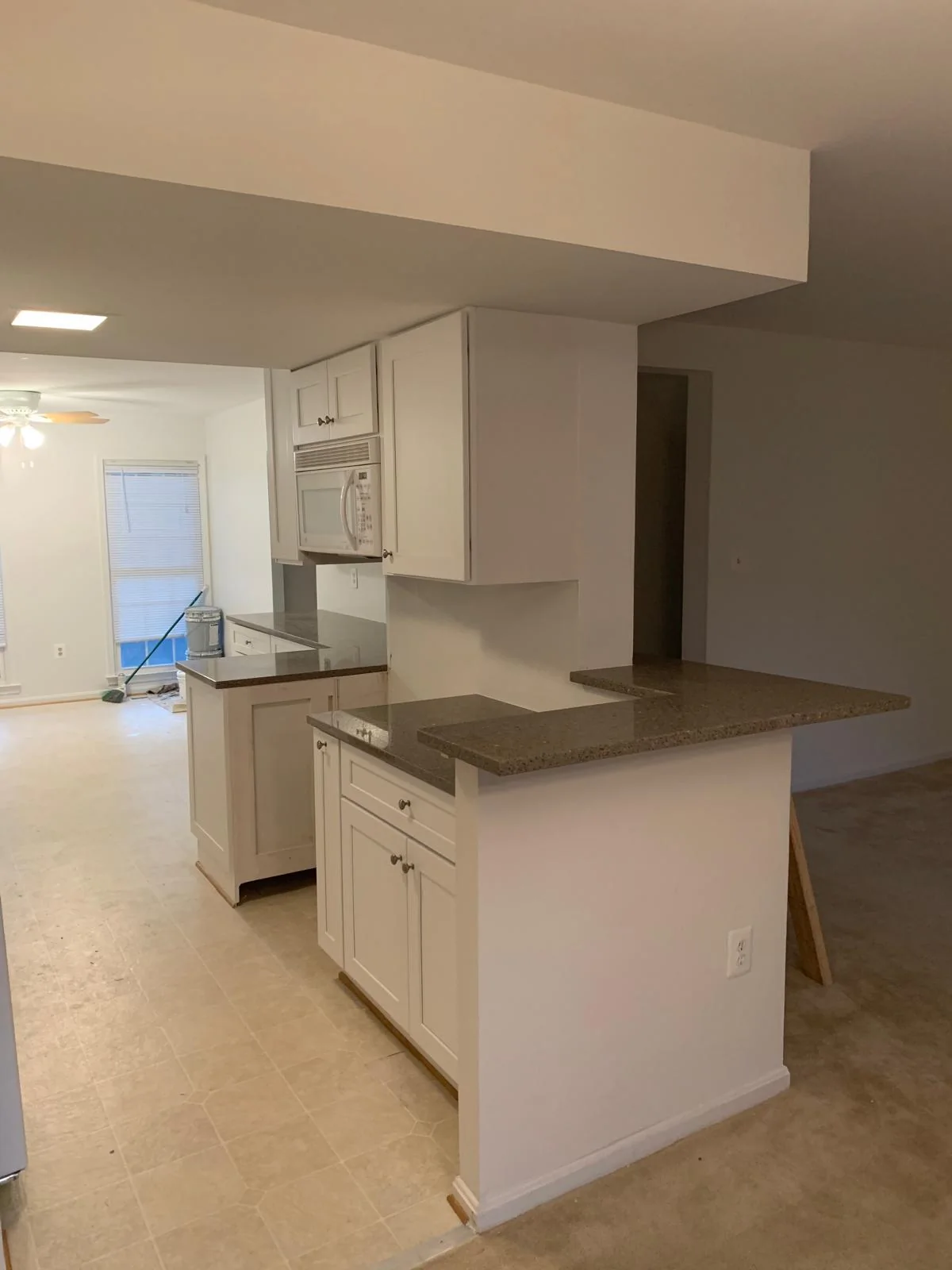 Open white kitchen layout with peninsula, cabinetry and stainless appliances