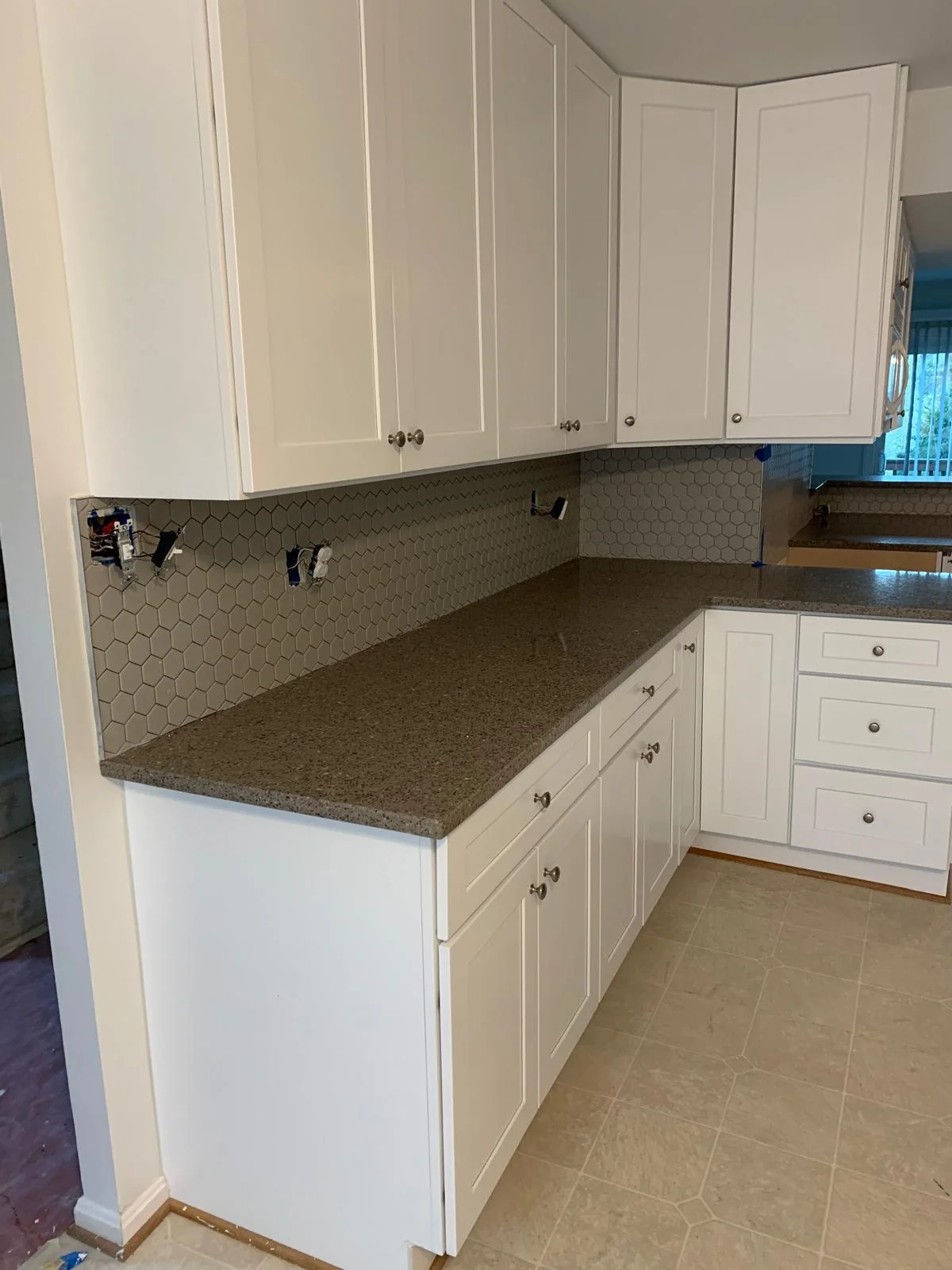 White kitchen peninsula and cabinetry with coordinated countertop finishes
