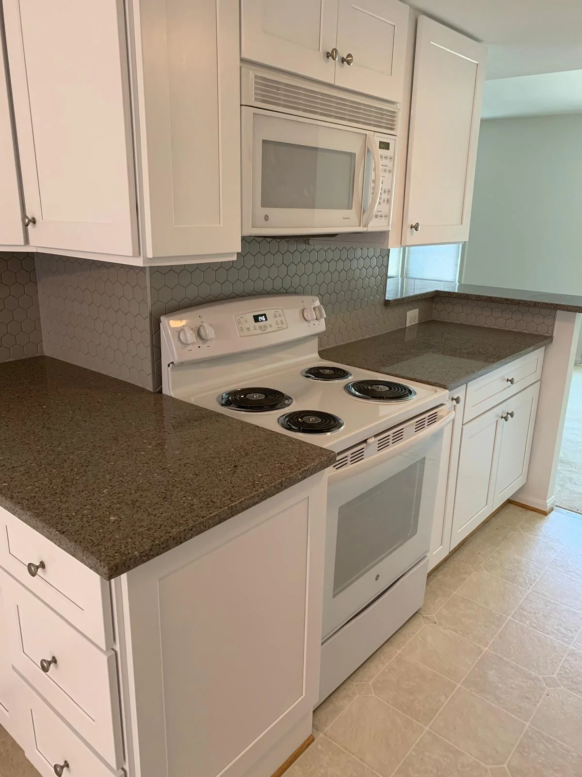 White kitchen range area with cabinetry, countertop and appliances