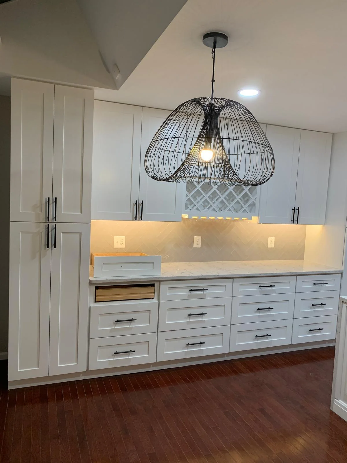 White kitchen wall cabinetry with integrated lighting and pendant fixture