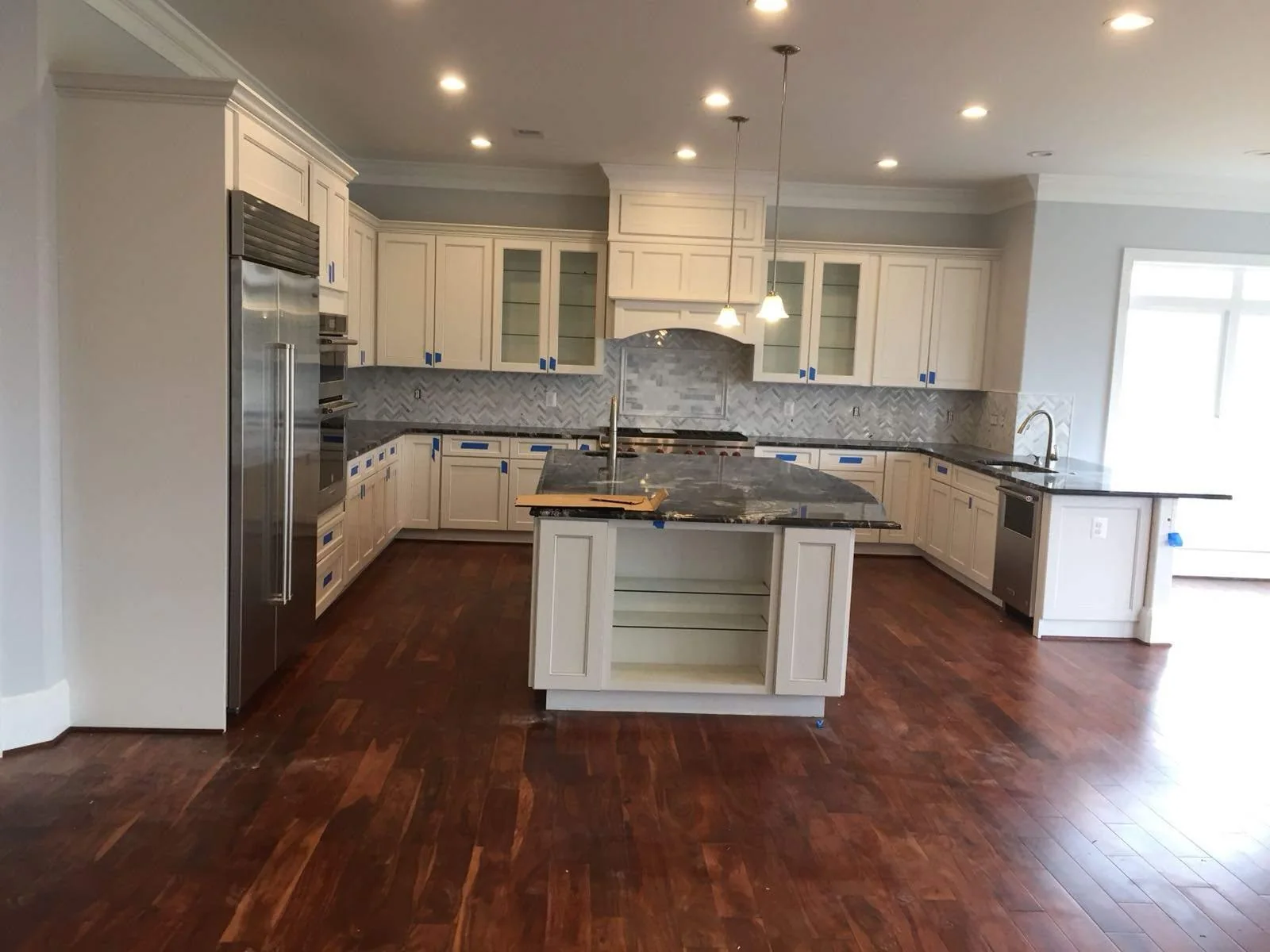 Wide view of a bright white kitchen with island and updated cabinetry