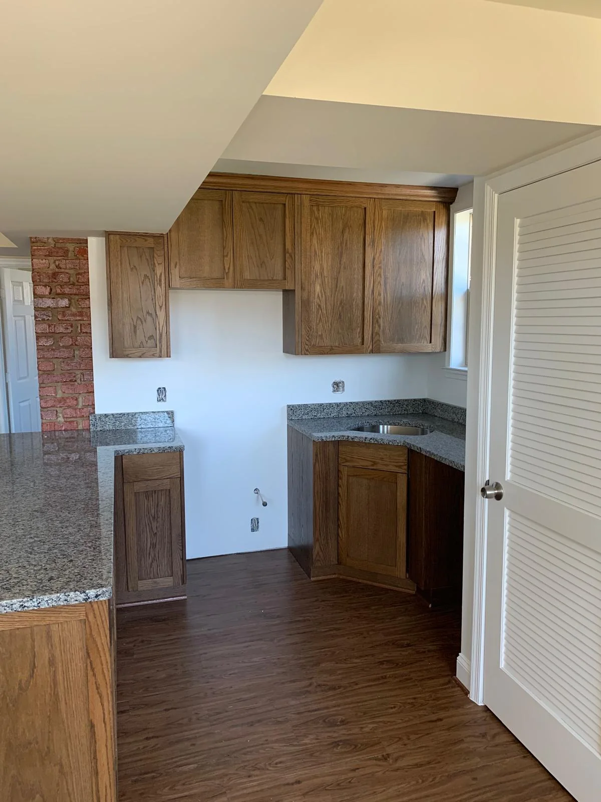 Kitchen with wood cabinetry, stone counters and adjacent doorway